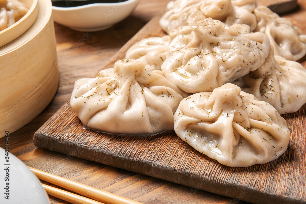 Board with tasty dumplings on table, closeup Board with tasty dumplings on table, closeup