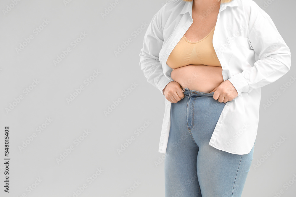 Fototapeta premium Weight gain and body image issues, woman struggling with tight jeans and excess belly fat
