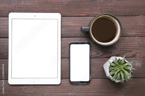 Tablet computer, mobile phone and cup of coffee on wooden background
