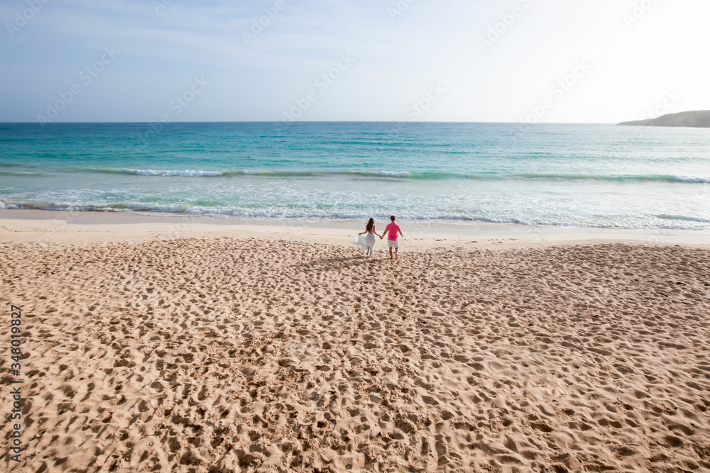 Romantic couple in love hugging, kissing and running on the sandy tropical Caribbean beach in Dominican republic landscape Romantic couple in love hugging, kissing and running on the sandy tropical Caribbean beach in Dominican republic landscape
