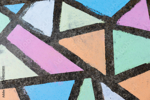 Brightly colored geometric shapes drawn in chalk along a side walk.