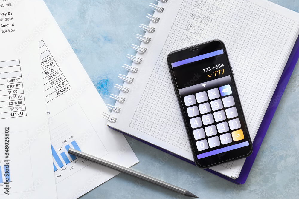 Calculator mobile application on screen of phone, stationery and documents on color background Calculator mobile application on screen of phone, stationery and documents on color background