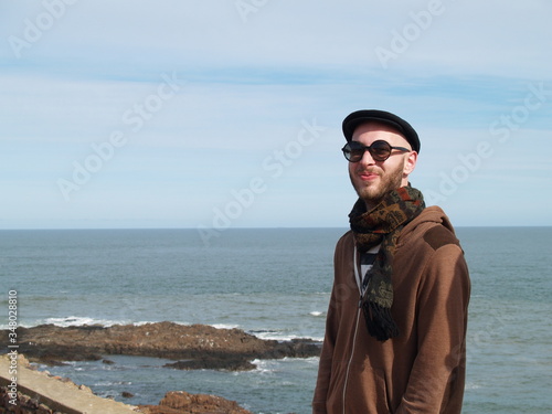 man with beard, sunglasses, beret and scarf on the sea