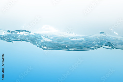 Fototapeta Naklejka Na Ścianę i Meble -  Water splash on blue background. Aqua flowing in waves and creating bubbles. Drops on the water surface feel fresh and clean.