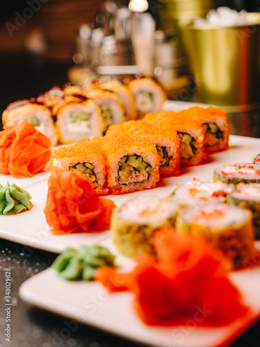 Rich assortment of sushi rolls on white ceramic plates, ready for serving