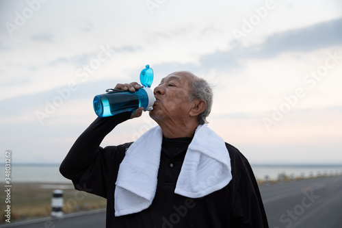 Close up Asian elderly drink water after exercise In the morning. health lifestyle and exercise Concept.