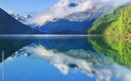 Mountain lake  beautiful reflection. Morning light  peaks in the clouds. Picturesque mountain landscape. Altai  a wild place in Siberia. Travel and summer vacation.