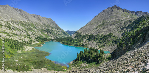 Panoramic mountain view, lake in the valley. Sunny day. Traveling in the mountains, trekking.