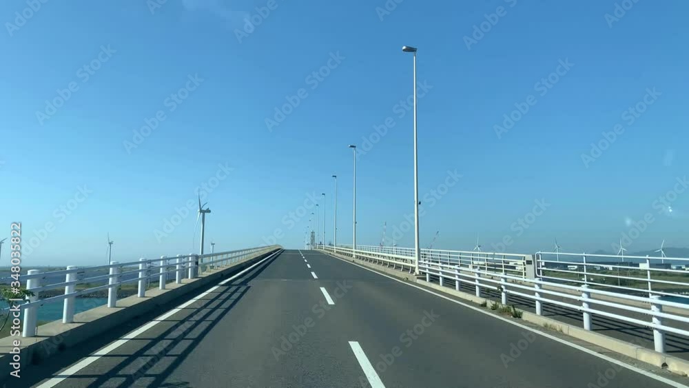 Crossing the bridge to wind turbine and solar farm. Renewable energy. Sunny day with blue sky. Crossing the bridge to wind turbine and solar farm. Renewable energy. Sunny day with blue sky.