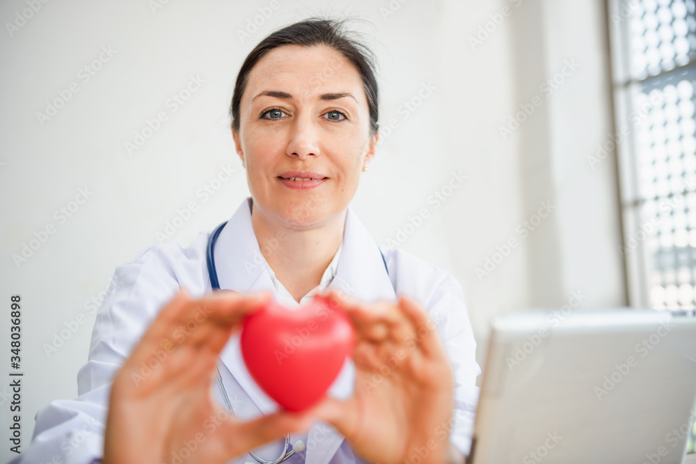 Medical Cardiologist Doctor is Holding Red Heart Give to Patient, Female Physician Doctor Showing Heart Model to Her Patients in Examination Room. Health Examining Check Up Medicine Cardiology Concept Medical Cardiologist Doctor is Holding Red Heart Give to Patient, Female Physician Doctor Showing Heart Model to Her Patients in Examination Room. Health Examining Check Up Medicine Cardiology Concept