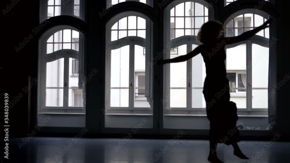 black female silhouette in a long skirt against the background of arched Windows. the woman dances, spreads her arms, spins, jumps. the camera is moving black female silhouette in a long skirt against the background of arched Windows. the woman dances, spreads her arms, spins, jumps. the camera is moving