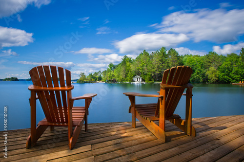 Canvas Two Muskoka chairs sitting on a wood dock facing a calm lake