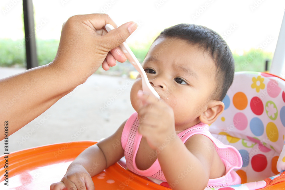 Asian boy 6 months old eating rice porridge and porridge dirty her mouth. Mother feed the son. Asian boy 6 months old eating rice porridge and porridge dirty her mouth. Mother feed the son.