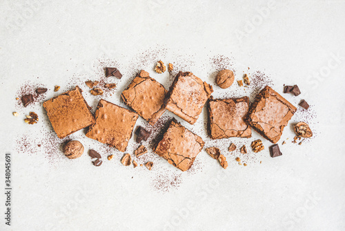 Obraz na płótnie Top view of freshly baked home made brownie cake arranged with nuts, chocolate and cocoa powder over white rustic background. w salonie