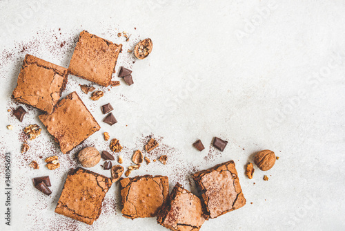 Obraz na płótnie Top view of freshly baked home made brownie cake arranged with nuts, chocolate and cocoa powder over white rustic background. w salonie