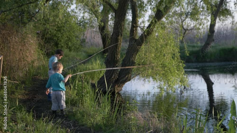 outdoor activities, cute boys by river play with sticks in water among trees and reeds during holidays in country outdoor activities, cute boys by river play with sticks in water among trees and reeds during holidays in country