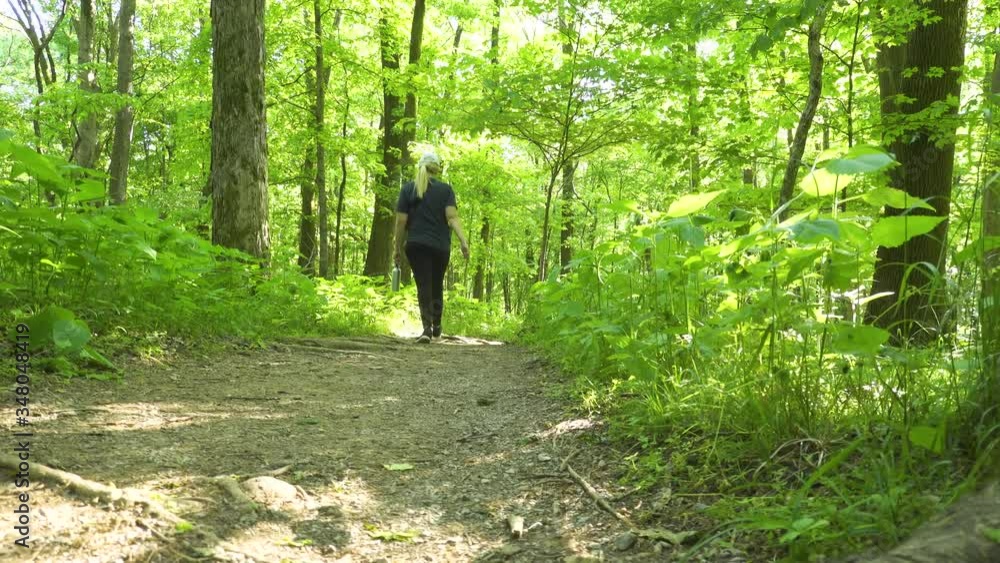 Low angle reveal of a young woman hiking in the forest Low angle reveal of a young woman hiking in the forest