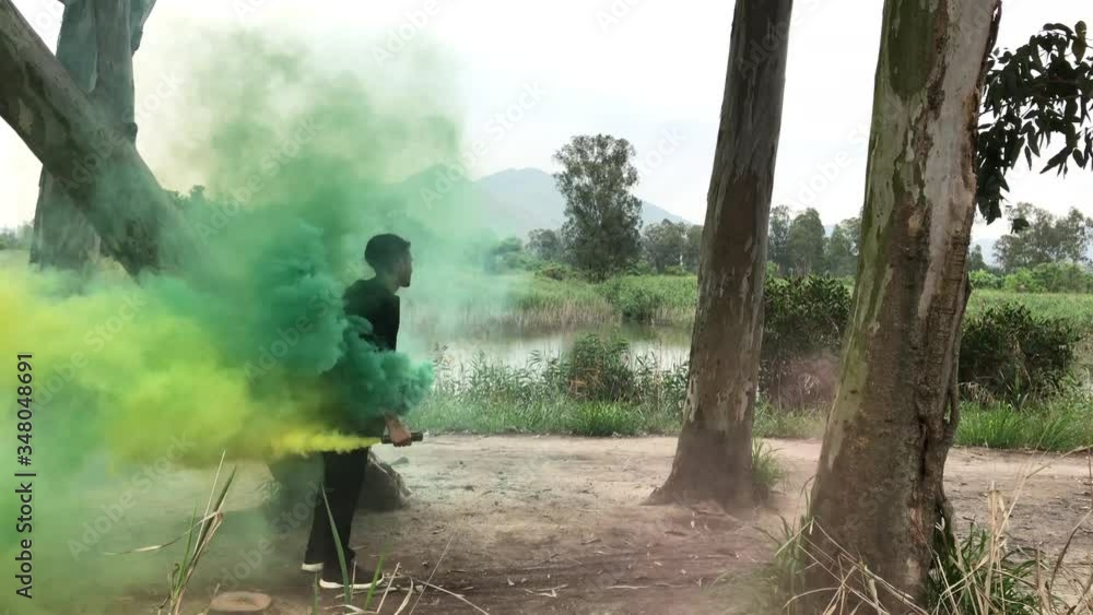 stuntman with green smoke performs wallflip on a tree trunk, parkour trick stuntman with green smoke performs wallflip on a tree trunk, parkour trick