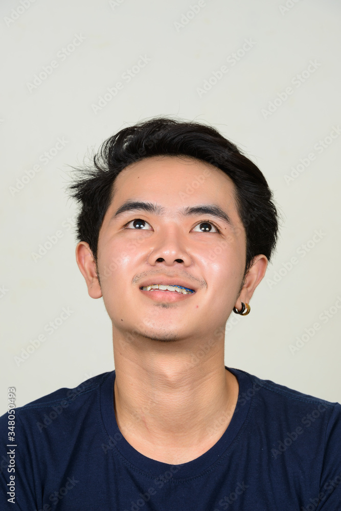 Portrait of happy young Asian man with braces thinking Portrait of happy young Asian man with braces thinking