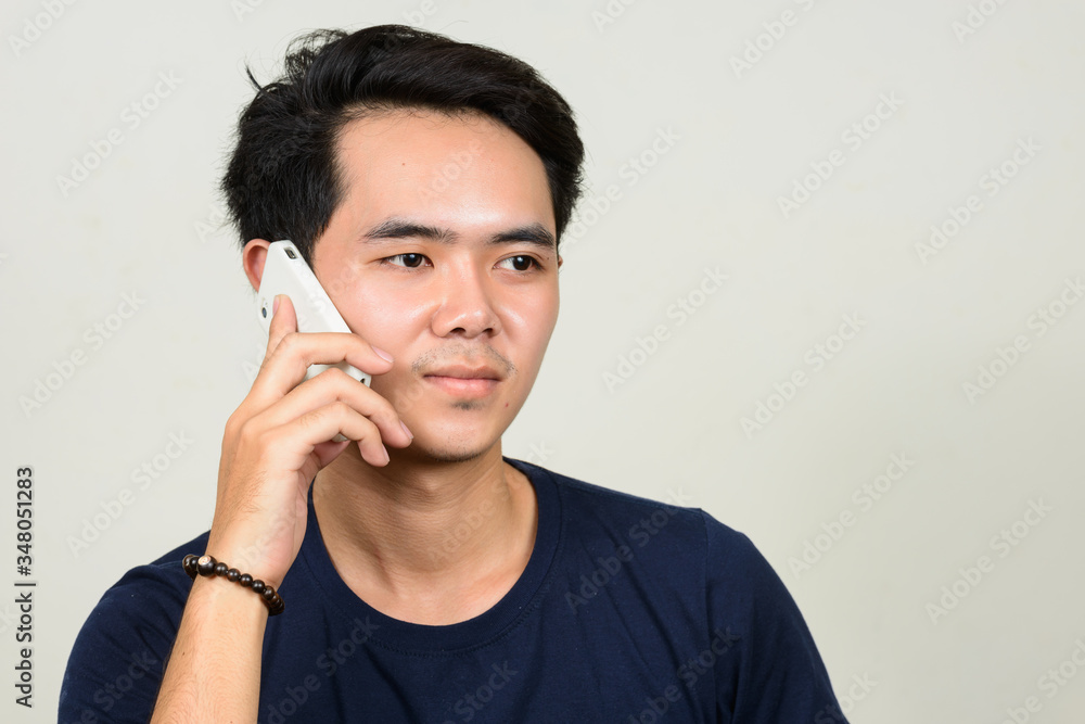 Portrait of young Asian man talking on the phone Portrait of young Asian man talking on the phone