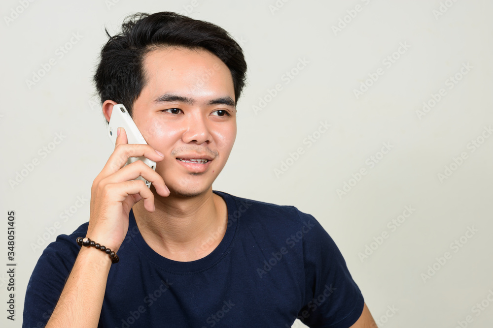 Portrait of happy young Asian man talking on the phone Portrait of happy young Asian man talking on the phone