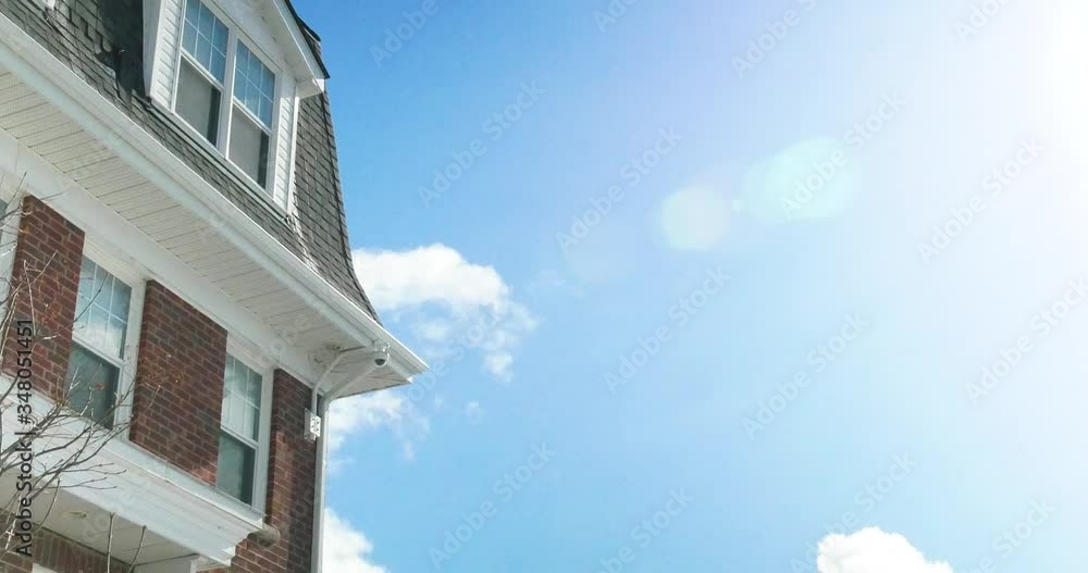 Sun Flare and Clouds in Beautiful Summer Sky above Local Residential Brick Townhouse