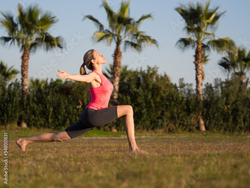 Evening female workout in vacation. Fit caucasian woman do exercise on the grass outdoor, selective focus. Lunge.