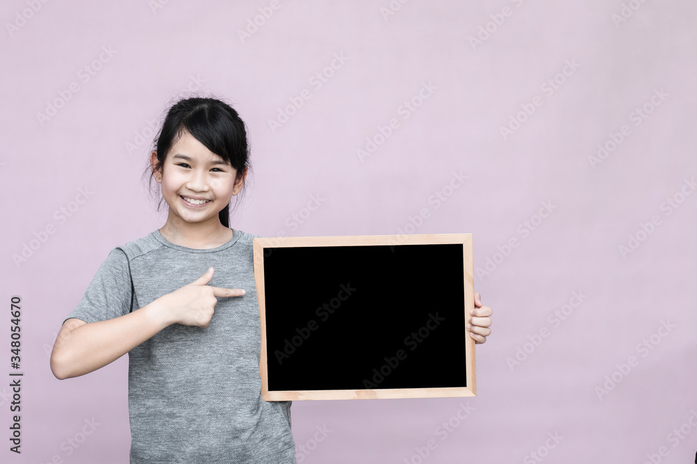 Little asian girl holding blackboard isolated on gray background.