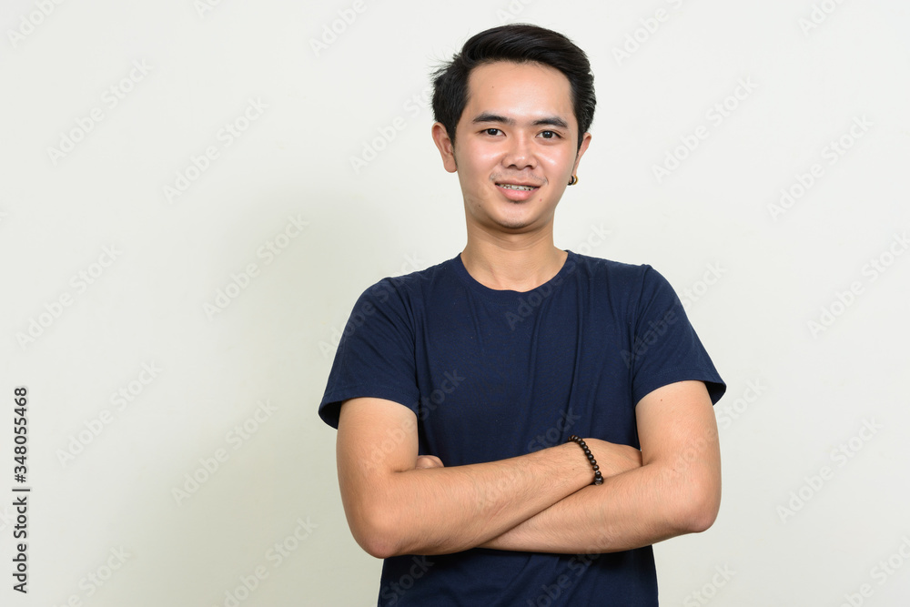 Fototapeta premium Portrait of happy young Asian man smiling with arms crossed