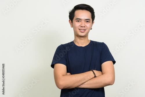 Portrait of happy young Asian man smiling with arms crossed