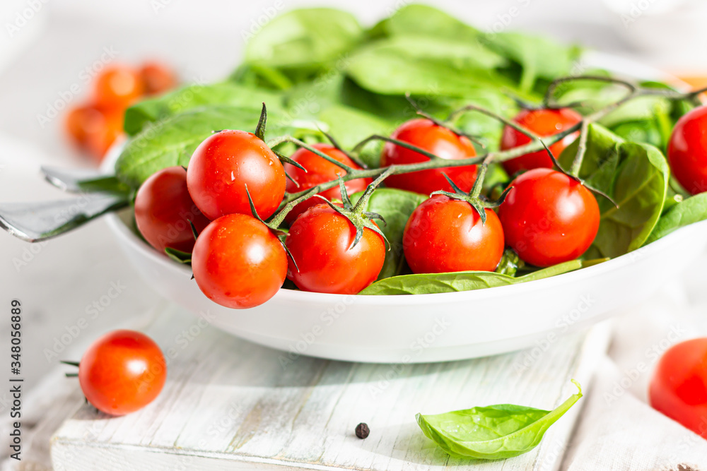 Baby spinach, red cherry and yellow tomatoes on white ceramic plate. Fresh vegetables. Summer harvest concept. Close up. Baby spinach, red cherry and yellow tomatoes on white ceramic plate. Fresh vegetables. Summer harvest concept. Close up.