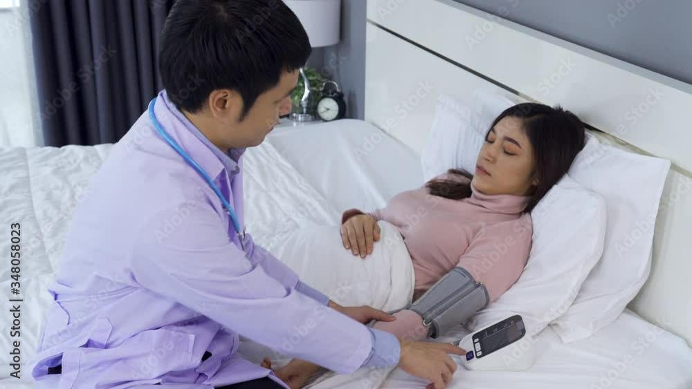 doctor measuring blood pressure of sick woman in bed doctor measuring blood pressure of sick woman in bed