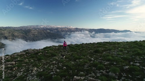 Male Hiker And Dog Walk Across Peak Of Mountain Range. Akoura, Lebanon. photo