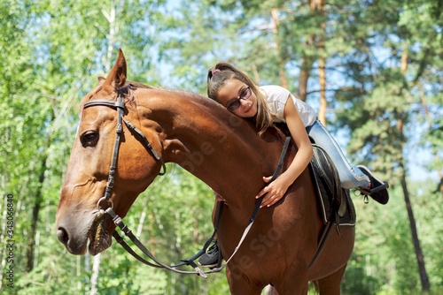 Girl child riding horse, summer horse ride in the forest, girl lovingly hugged horse © Valerii Honcharuk