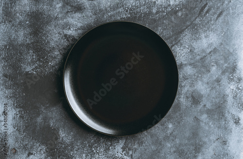 Clean black plate on the rustic background. Selective focus. Shot from above.