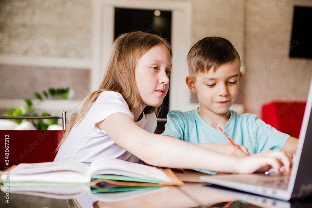 Boy and girl, brother and sister study at home. Older sister helps younger brother do homework Boy and girl, brother and sister study at home. Older sister helps younger brother do homework