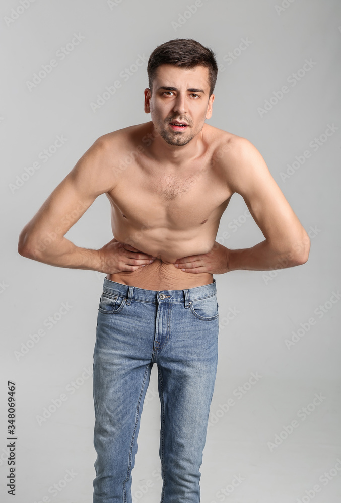 Young man with anorexia on grey background