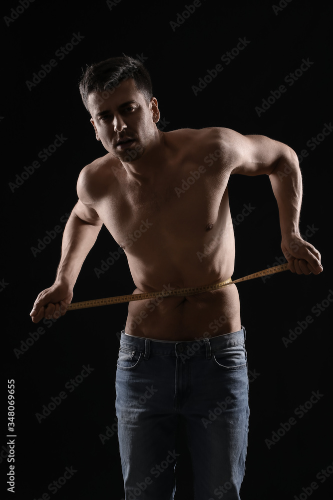 Sick man measuring his waist on dark background. Concept of anorexia Sick man measuring his waist on dark background. Concept of anorexia