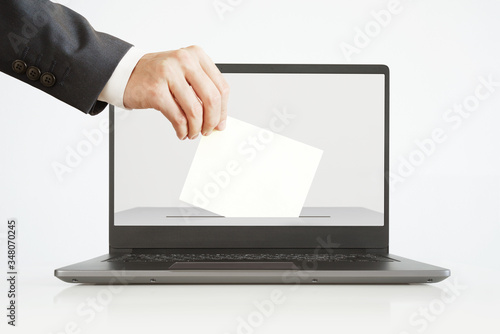 Voting Online Concept. Man Putting a Ballot into a Laptop. photo