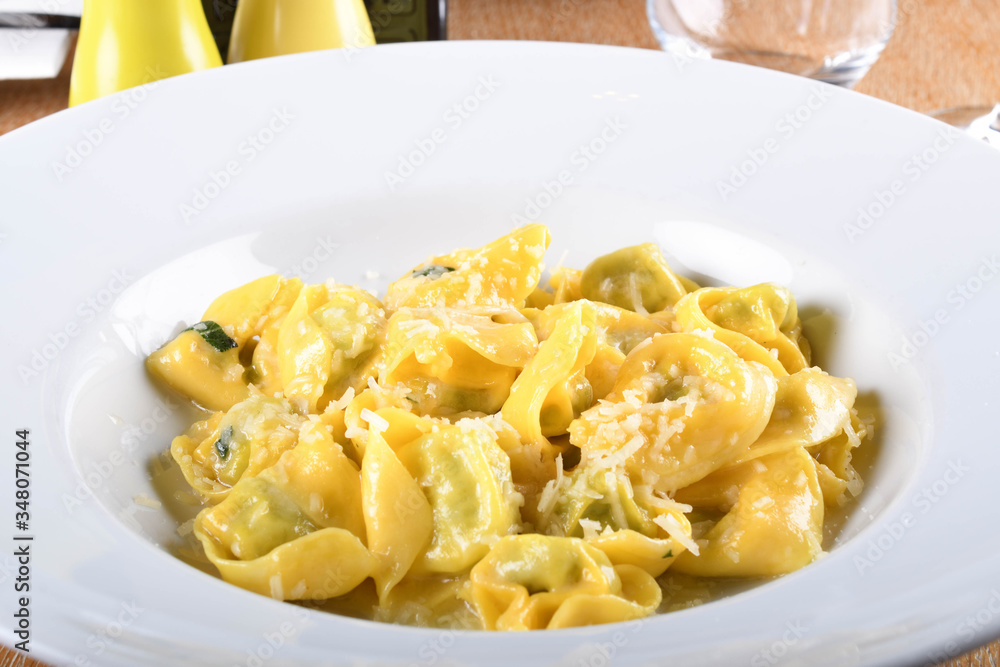 Tortellini with ricotta cheese and spinach, butter, sage sauce, grated parmesan. Parmigiano-Reggiano flakes