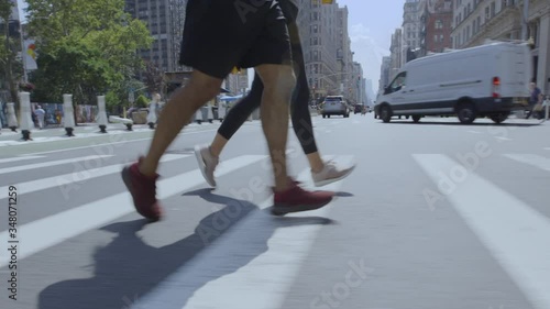 Two runners jogging over a crosswalk on 5th Avenue in the flatiron district of manhattan, new york city. Close up of their feet.