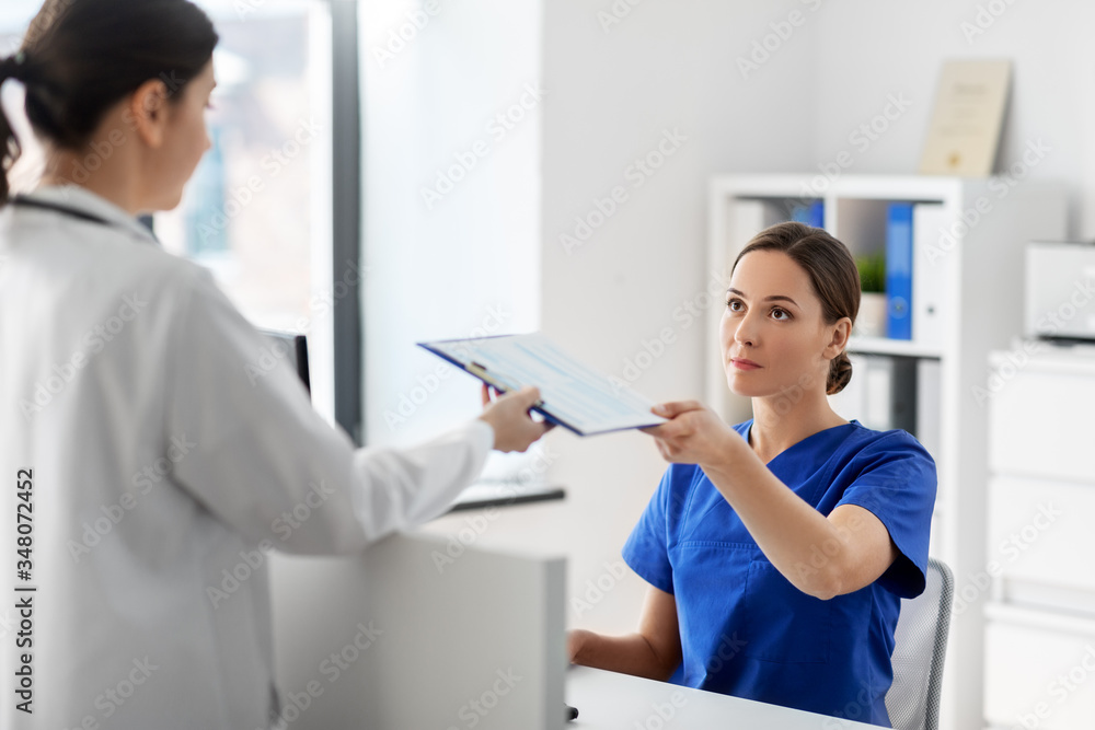 Obraz premium medicine, healthcare and people concept - doctor and nurse with clipboard at hospital