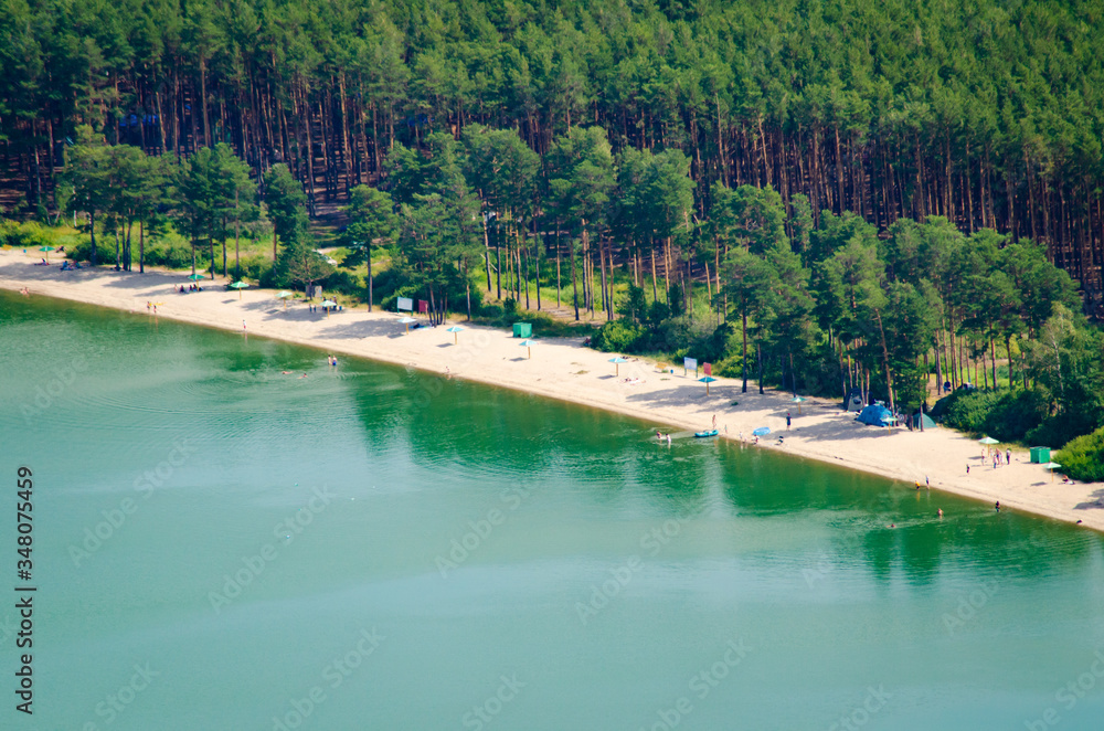Beach with blue water aerial view from the drone of a lake or sea with pine forest landscape