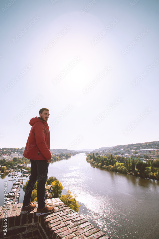 Young man with view of the Prague, Czech Republic. Touristic travel photo conception. Man stand on brick wall near the river