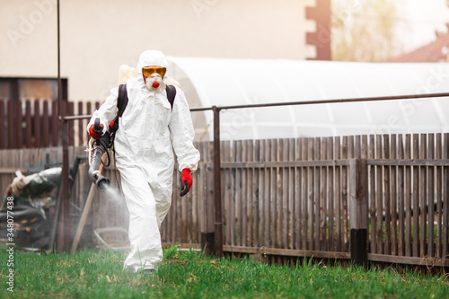 Disinfection of recreation parks from coronavirus virus, worker in protective suit with spray