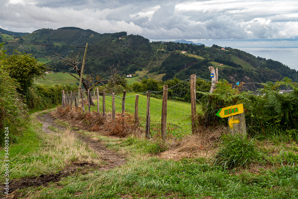 Hiking route leading to Deba, with pointers to the town in Basque Country, Spain. Camino de Santiago on a cloudy day.