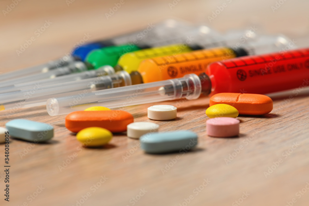 Concept of treatment options for COVID virus infection. Colorful syringes and tablets close-up. Concept of treatment options for COVID virus infection. Colorful syringes and tablets close-up.