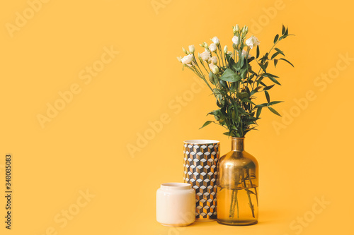 Different vases with bouquet of flowers on color background