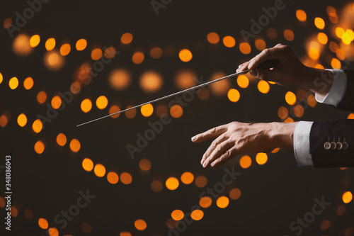 Hands of male conductor on dark background with defocused lights