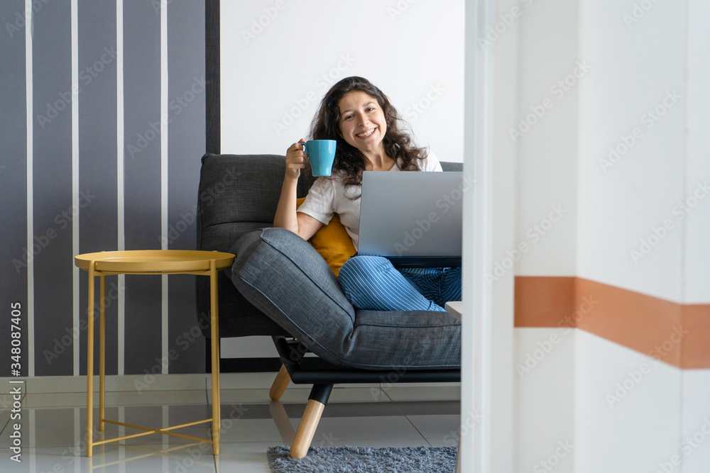 Beautiful girl sitting with a laptop on a sofa in a stylish room. Work from home. Work atmosphere in a good mood Beautiful girl sitting with a laptop on a sofa in a stylish room. Work from home. Work atmosphere in a good mood
